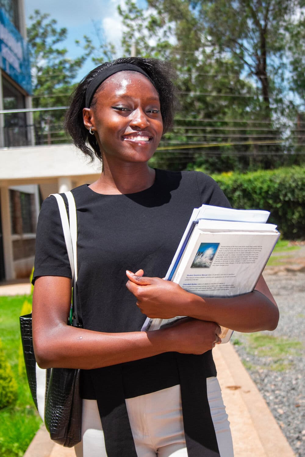 A Mahanaim College student on campus, holding her books